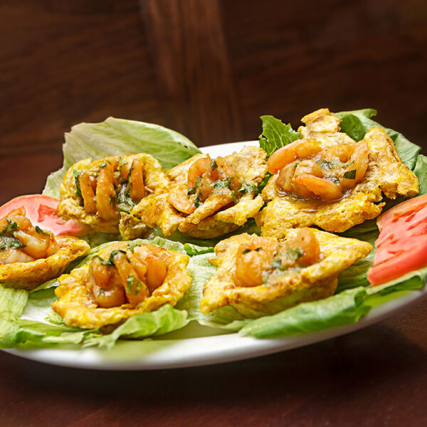 Fried Plantains stuffed with seasoned shrimp or chicken in a garlic or red sauce - Tostones